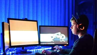Image représentant un jeune gamer avec devant lui 3 ecrans de PC